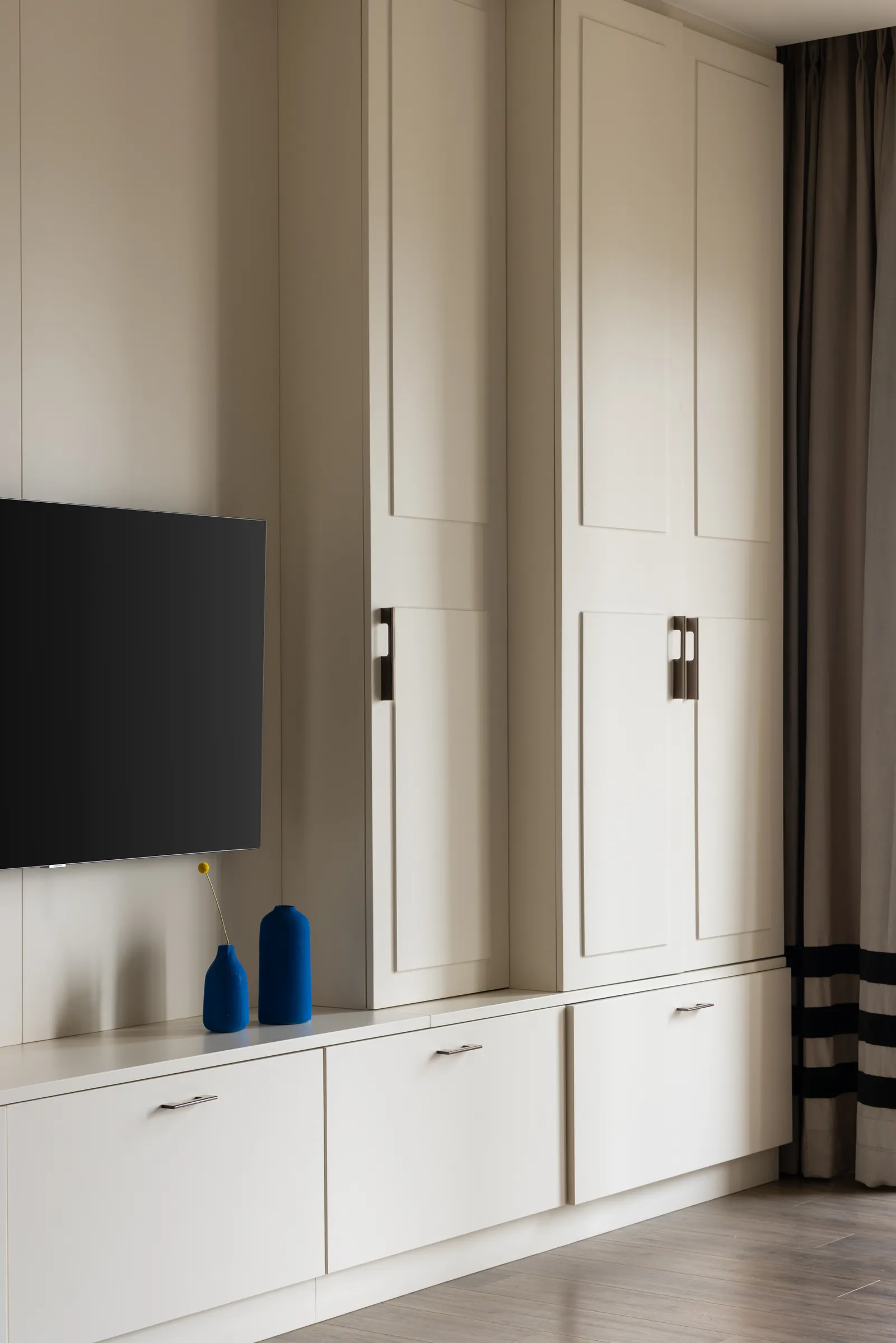 Bedroom TV wall with tall white wardrobes — Seema Katta Svasa